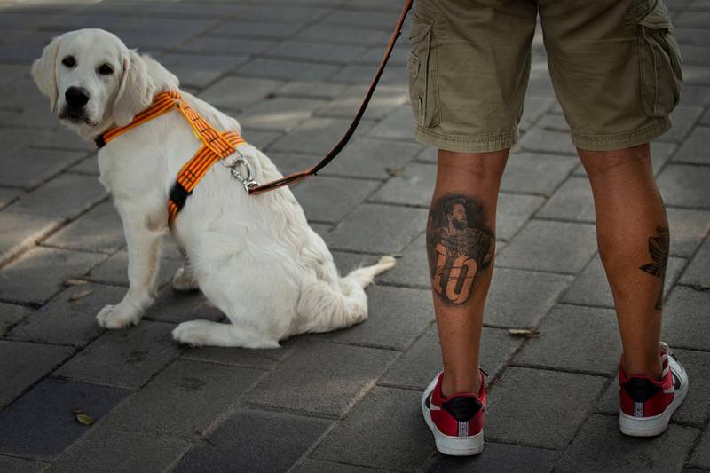 A tattoo of Lionel Messi on the leg of a Barcelona fan as he waits to see players arriving for coronavirus tests. EPA