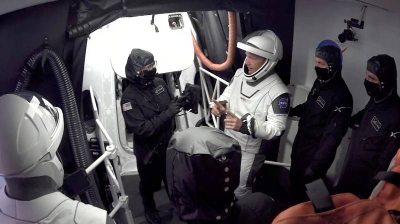 Doug Hurley, centre, and Bob Behnken confer with technicians after leaving the Crew Dragon capsule.  AP
