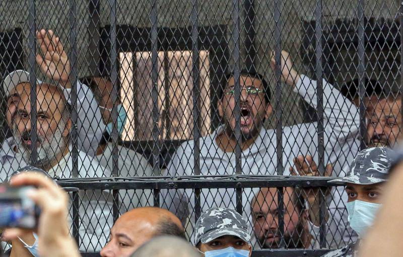 Men charged with illegal excavation and trafficking of antiquities, react in the accused dock during the verdict announcement session of their trial in Egypt's capital Cairo on April 21, 2022.  - The court handed Egyptian businessman Hassan Ratib a 5-year jail sentence, and former MP Alaa Hassanein 10 years, local media reported.  (Photo by Khaled KAMEL  /  AFP)