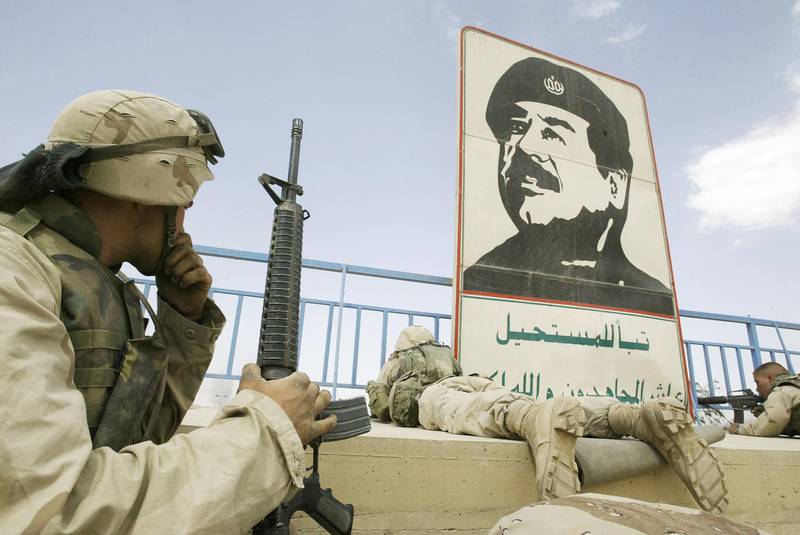 US marines take position near a portrait of then Iraqi leader Saddam Hussein in Baghdad, during the Second Gulf War in 2003. AFP