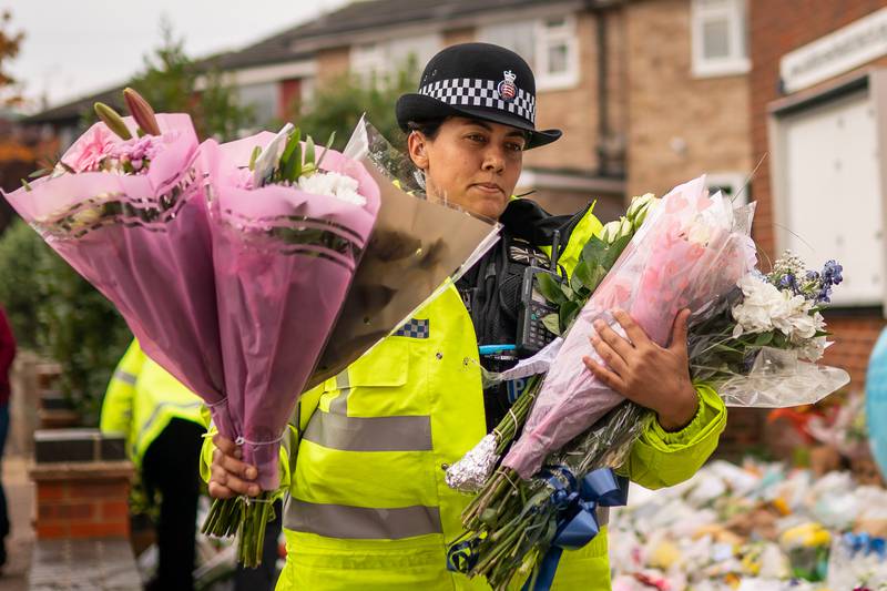 A Police officer arranges flowers and tributes outside Belfairs Methodist Church in Eastwood Road North. PA