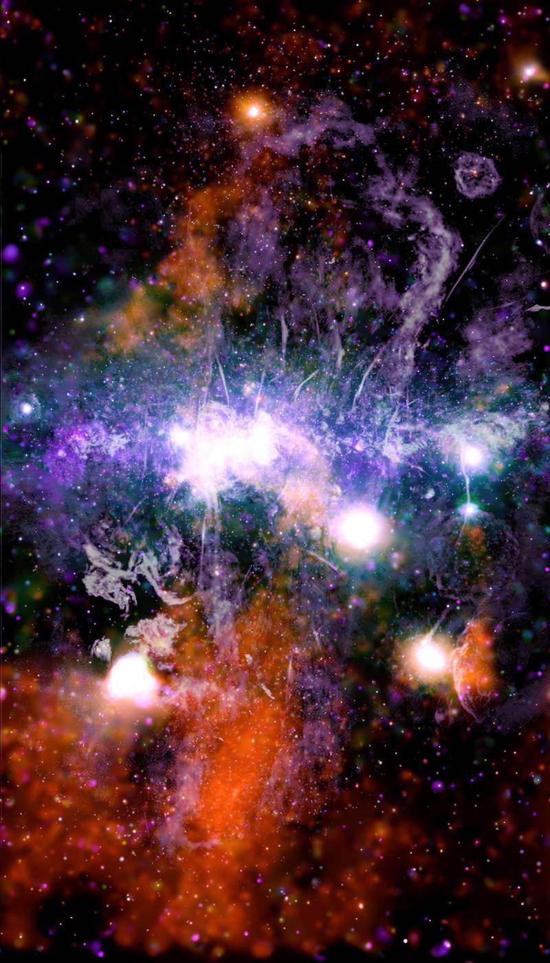 This false-color X-ray and radio frequency image made available by NASA on Friday, May 28, 2021 shows threads of superheated gas and magnetic fields at the center of the Milky Way galaxy. X-rays detected by the NASA's Chandra X-ray Observatory are in orange, green, blue and purple, and radio data from the MeerKAT radio telescope in South Africa are shown in lilac and gray. The plane of the galazy is horizontal, in the center of this vertical image. Astronomer Daniel Wang of the University of Massachusetts Amherst said Friday he spent a year working on this, while stuck at home during the pandemic. (NASA/CXC/UMass/Q.D. Wang, NRF/SARAO/MeerKAT via AP)
