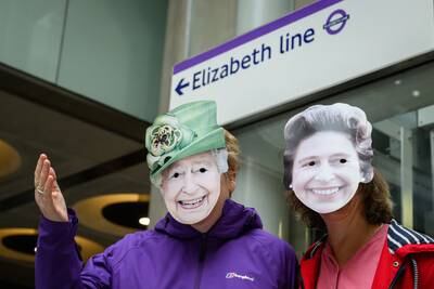 Passengers wearing Queen Elizabeth II masks – after whom the line is named – pose under a network sign. Getty Images