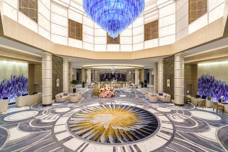 The grand lobby features muted tones and a pop of colour via the blue chandelier