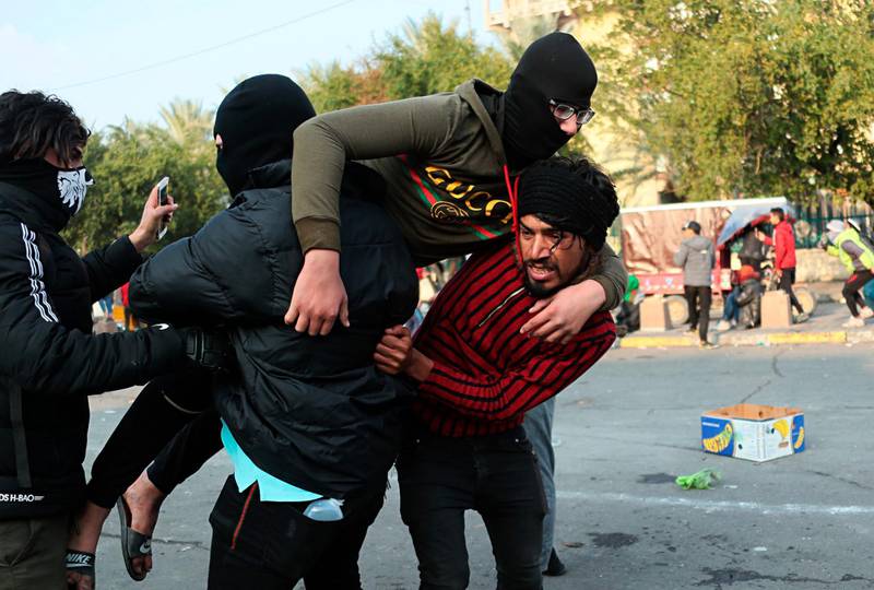 A protester is helped after Riot police fired tear gas during clashes with anti-government protesters in Baghdad. AP Photo
