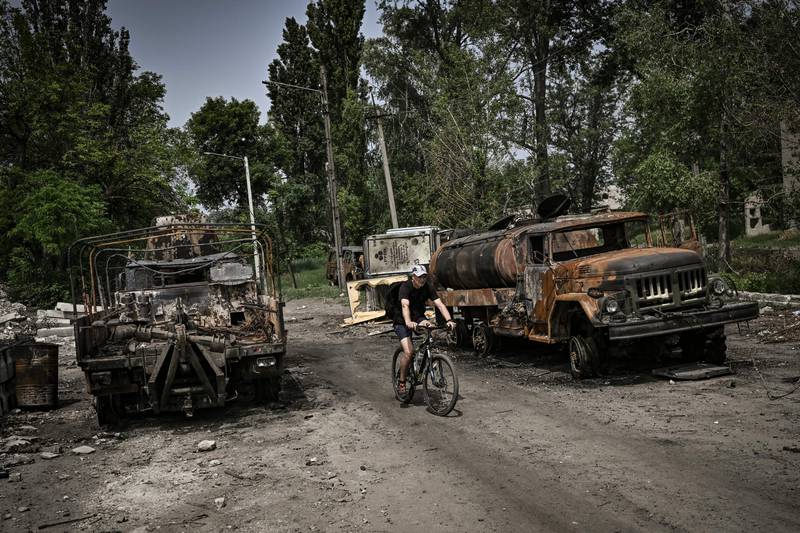 A man passes two destroyed military lorries in Lysychansk. AFP