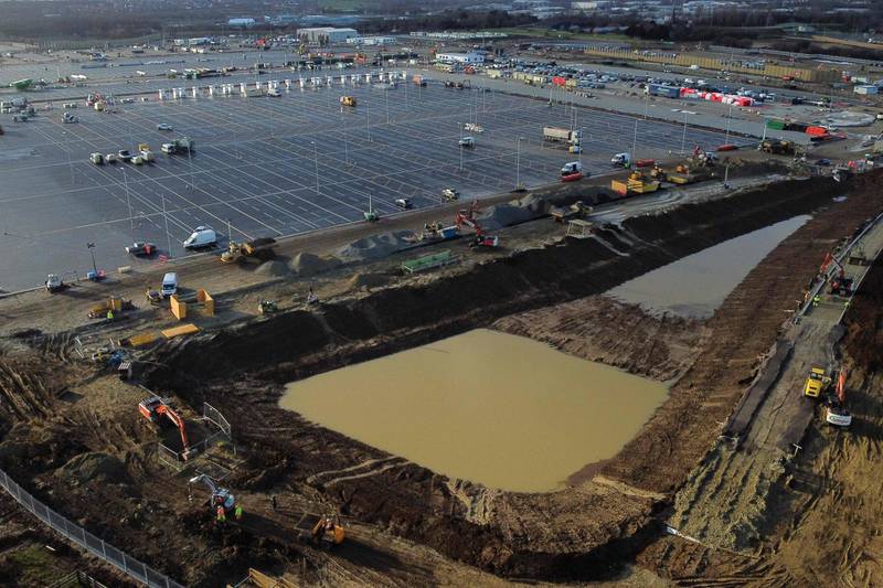 An aerial picture shows construction work continuing at the site of a lorry park being built between the villages of Sevington and Mersham, near the M20 motorway near Ashford in Kent, south east England on December 17, 2020. Questions were asked in the House of Lords today on the state of preparedness of the lorry park at Sevington. A proposed customs control area will not be ready, but transport minister Lady Vere said that the facility, which should hold up to 1,200 lorries, will open as planned on January 1, 2021. / AFP / BEN STANSALL
