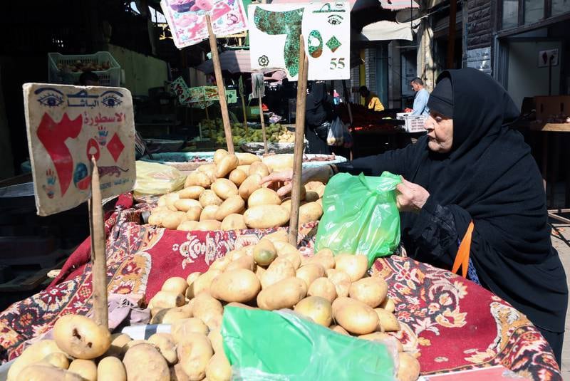 A woman buys potatoes at an outdoor market in Cairo's Abdeen district. EPA
