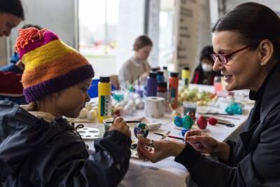 Myroslava Perevalska (R), an artist who fled Kyiv, helps a Ukrainian girl paint Easter eggs in Berlin. Getty Images