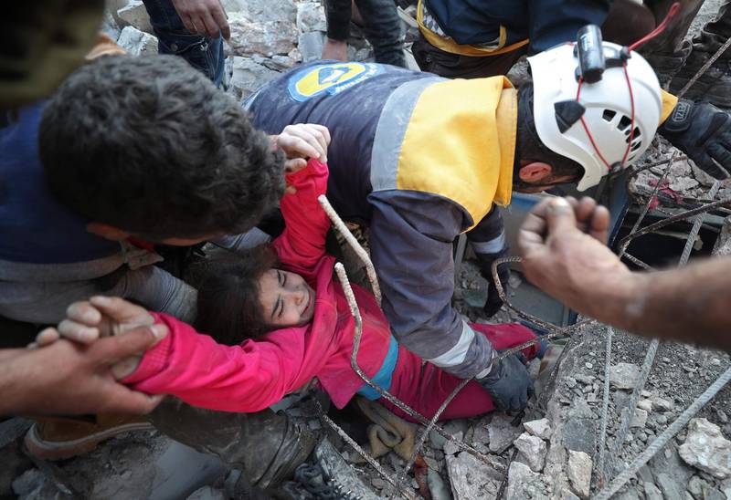 Members of the Syrian Civil Defence, also known as the White Helmets, rescue an injured girl from the rubble of a building in the village of Tal Mardikh in Syria's north-west Idlib province AFP