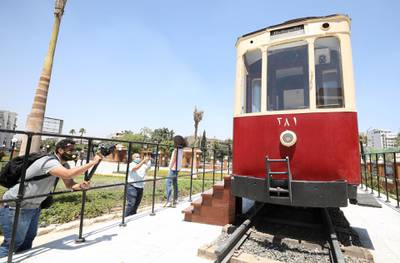 People stand near one of the restored old Heliopolis trams displayed at the Baron Empain Palace's garden after it was reopened to visitors in the suburb of Heliopolis. EPA