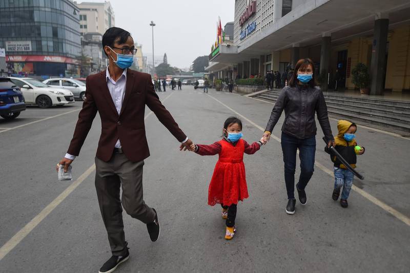 A Vietnamese family wearing protective face masks walk outside a railway station in Hanoi.  AFP