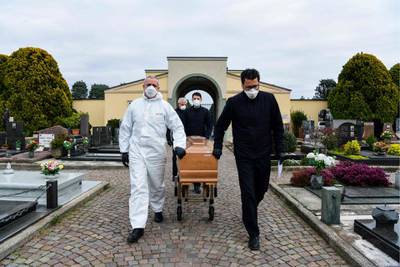 Pallbearers pull the coffin of a deceased person for a funeral ceremony into the cemetery of Grassobbio, Lombardy. AFP