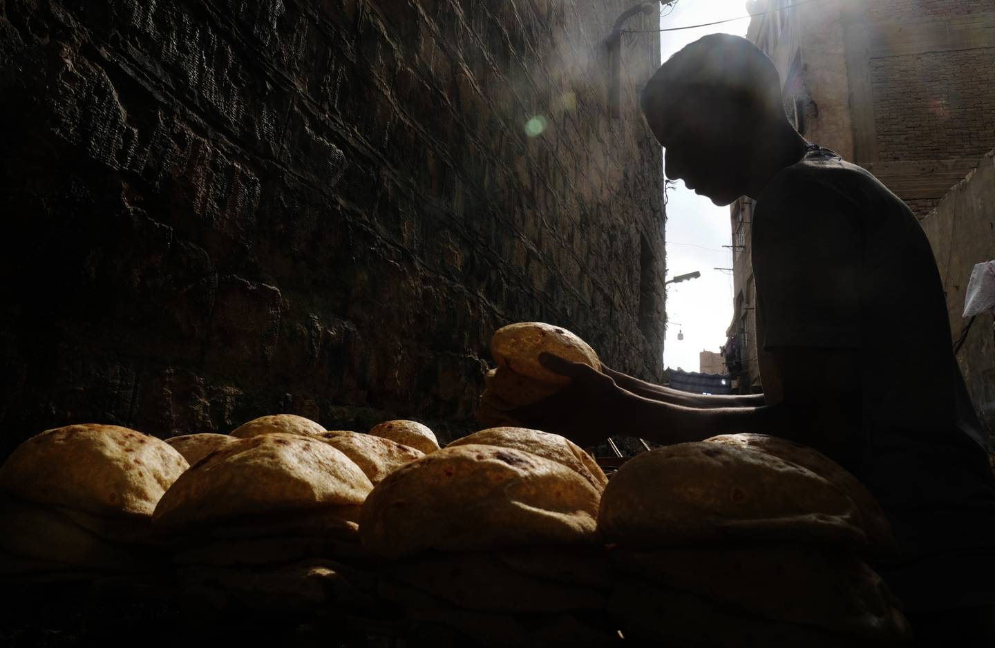 A baker stacks traditional baladi flatbread outside a bakery in Cairo. The war in Ukraine has hit grain imports. AP