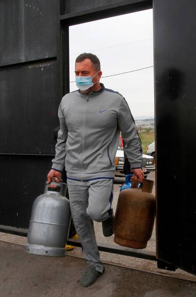 A mask-clad man carries two gas cylinders in the southern Lebanese city of Sidon on January 13, 2021 as the Lebanese rush to stock up on provisions one day before a total lockdown due to the spread of the COVID-19 pandemic. AFP