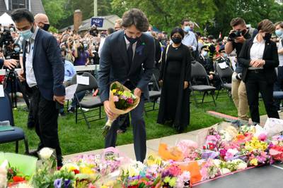 Mr Trudeau places flowers on a memorial. Reuters