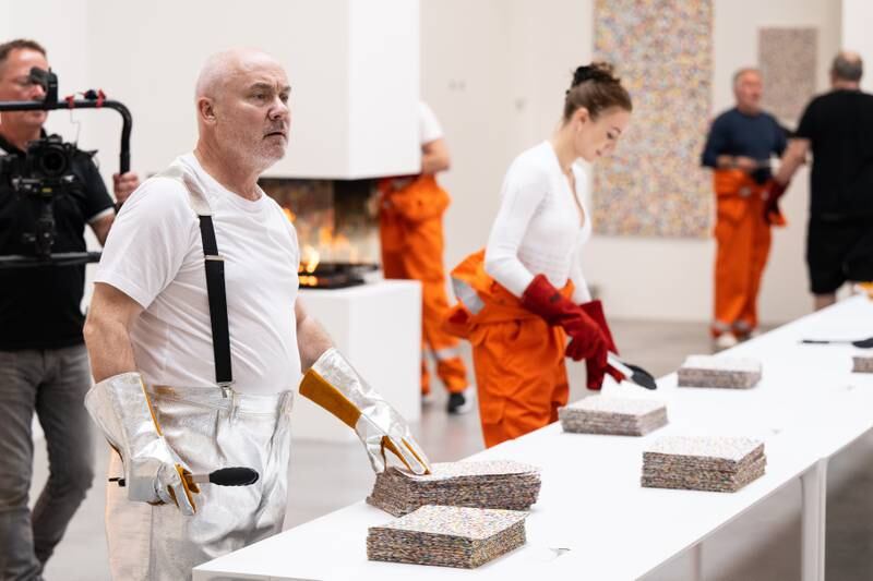 The artist was dressed in silver metallic boiler-suit trousers and matching fire safety gloves as he collected each piece and burned it in a contained fire box. Getty Images