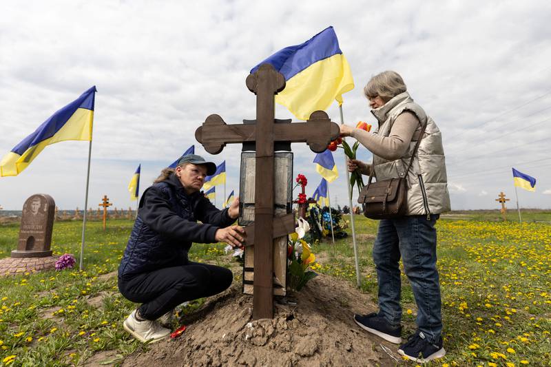 Ukrainian women visit the grave of a relative. Reuters