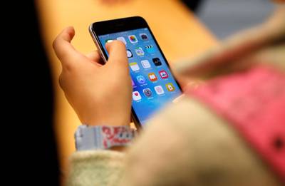 FILE - In this Sept. 25, 2015, file photo, a child holds an Apple iPhone 6S at an Apple store on Chicago's Magnificent Mile in Chicago. The World Health Organization Wednesday, April 24, 2019, issued its first-ever guidance for how much screen time children under 5 should get: not very much, and none at all for those under 1. (AP Photo/Kiichiro Sato, File)