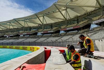 Workers ensure the circuit's safety barriers are up to muster