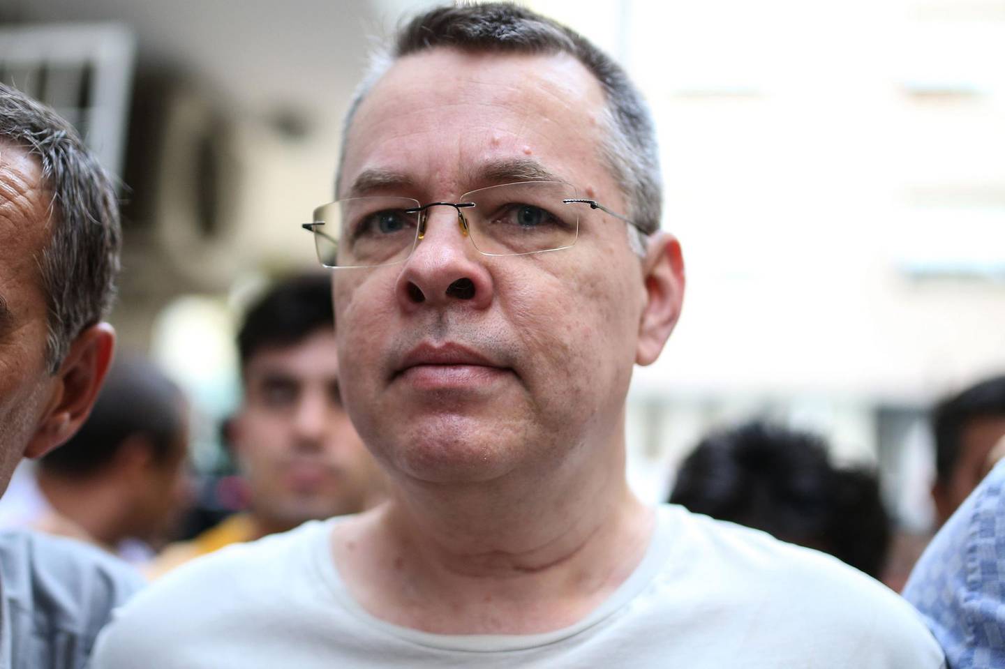 (FILES) In this file photograph taken on July 25, 2018, US pastor Andrew Craig Brunson is escorted by Turkish plain clothes police officers to his house in Izmir. - President Donald Trump's administration has rejected Turkey's offer to condition the release of an American pastor on clearing a top Turkish bank of billions of dollars in US fines, media reported August 20, 2018. Washington and Ankara are locked in a bitter feud over the nearly two-year jailing of Andrew Brunson over disputed terror charges, which has triggered a trade row and sent the lira into a tailspin. (Photo by - / AFP)