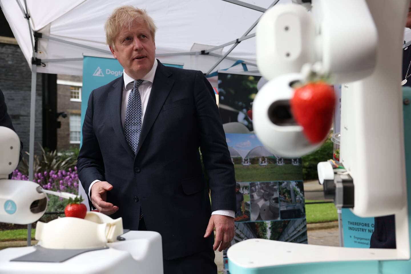 Boris Johnson visits a robotic fruit picker stall at a street market in Downing Street, London, on Monday. EPA