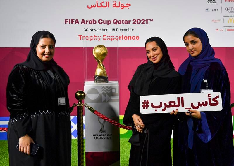 Women pose next to the Fifa Arab Cup Trophy.