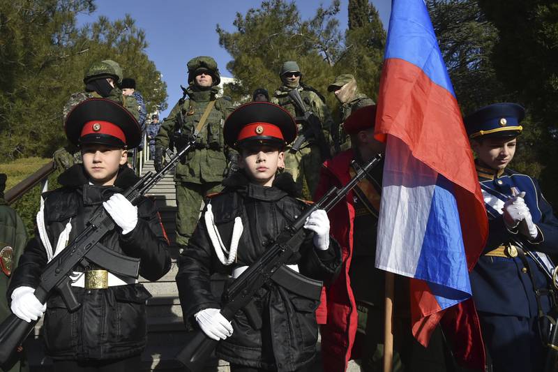 Students of a military school and Russian soldiers in Crimea stand in front of plaques with the names of Russian troops who died during fighting in Ukraine. AP