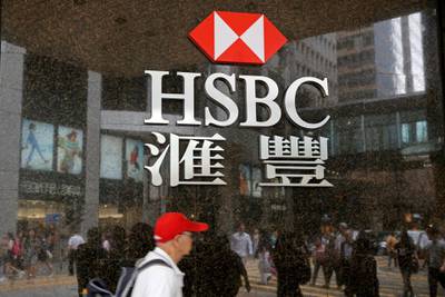 People walk past a branch of HSBC bank in Hong Kong, Friday, May 4, 2018. Global bank HSBC says pretax profits dipped in the latest quarter because of higher operating costs. The bank also said Friday that it's planning to buy back up to $2 billion in shares. It was its first quarterly earnings report under new Chief Executive John Flint, who took over in February.(AP Photo/Kin Cheung)