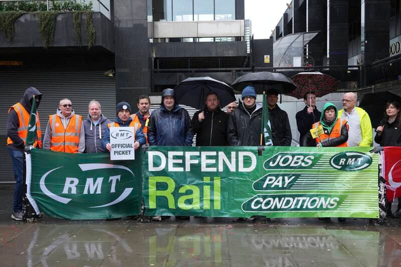 Mick Lynch, general secretary of the RMT, sixth left in blue jacket, joins union members on the picket line during a rail strike outside Euston station in London. AP