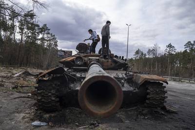 Local residents stand on top of a Russian tank on the outskirts of Kyiv. AP