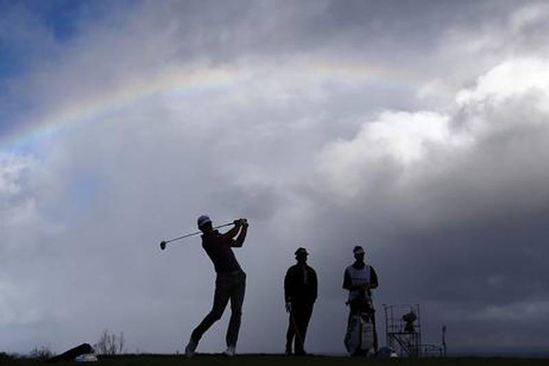 Dustin Johnson hits a tee shot under a rainbow as the Tournament of Champions finally begins in Hawaii.
