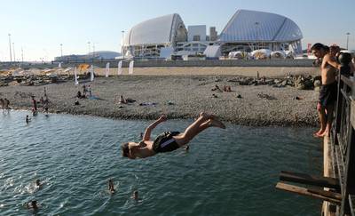 A boy jumps into the black sea in front of the Fisht stadium in Sochi, Russia. Andre Penner / AP Photo