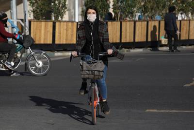 A woman rides her bicycle wearing a face mask in downtown Tehran. AP