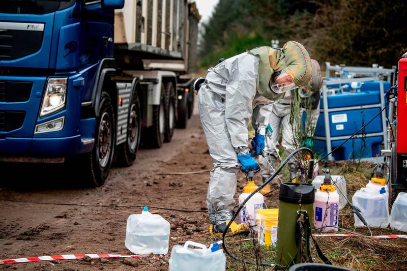 Men in hazmat suits prepare liquid to clean trucks as members of Danish health authorities assisted by members of the Danish Armed Forces dispose of dead mink in a military area near Holstebro, Denmark on November 9, 2020.  Danish mink will be buried in mass graves on military land as the country's incinerators and rendering plants struggle to keep up, the Danish environmental and health authorities announced. Denmark will cull about 17 million mink after a mutated form of coronavirus that can spread to humans was found on mink farms.  - Denmark OUT
 / AFP / Ritzau Scanpix / Morten Stricker
