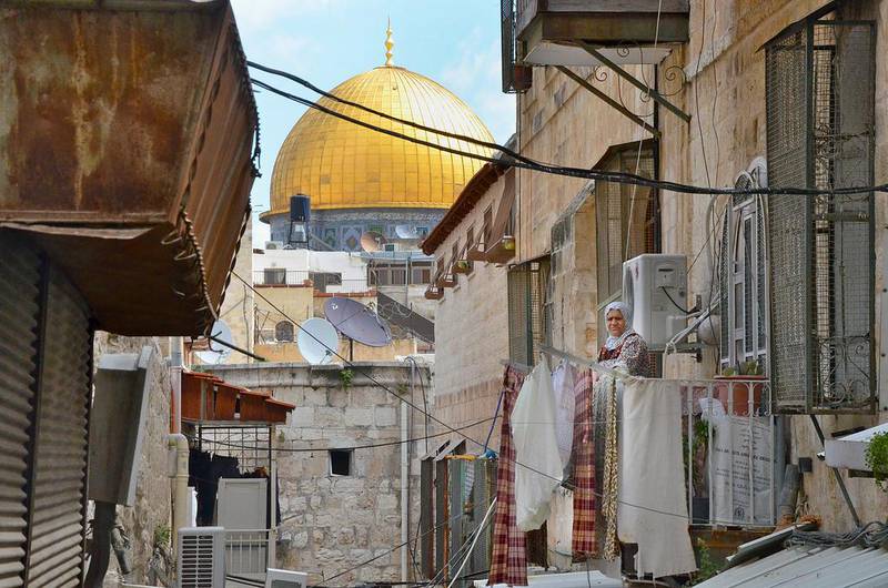 A Palestinian woman stands on her balcony with the Dome of the Rock in the background. Kate Shuttleworth for The National