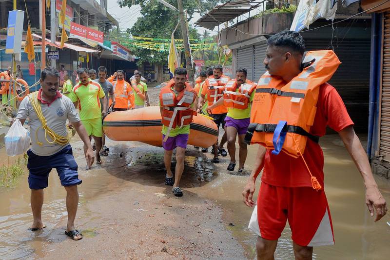 Kerala and Tamil Nadu Fire Force personnel carry a dinghy during a rescue operation for flood victims in Annamanada village in Thrissur District, Kerala. AFP