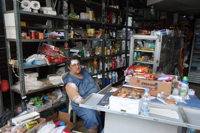 An injured Lebanese shop owner sits at her desk selling her wares.  EPA