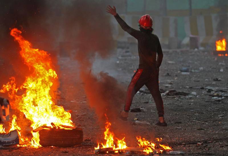 An Iraqi protester gestures next to burning tyres amid clashes with security forces at Baghdad's Khallani square during ongoing anti-government demonstrations. AFP