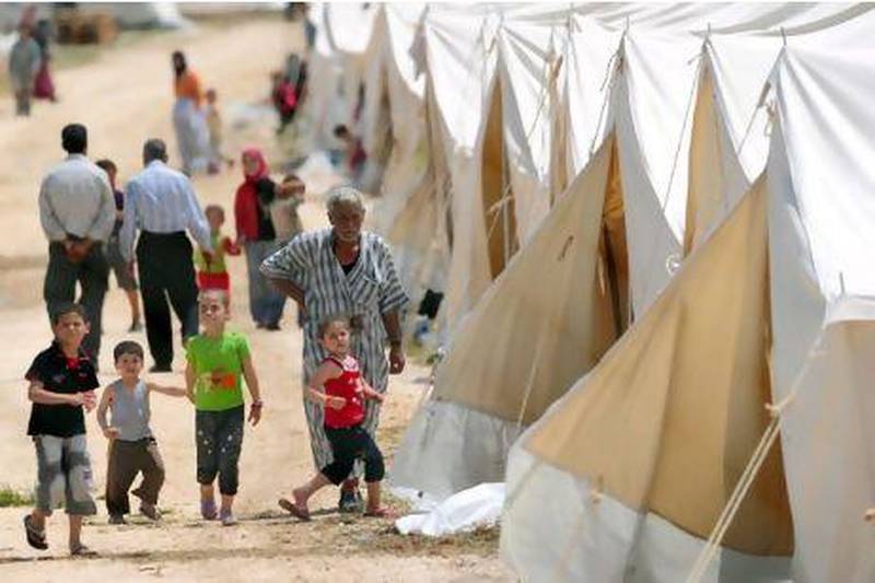 Syrian refugees walk past tents at the Boynuyogun Turkish Red Crescent camp near the Syrian border yesterday. More than 5,000 people have fled the security crackdown in Syria.