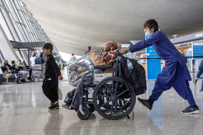 A child flown from Kabul pushes a wheelchair with a woman at Washington Dulles International Airport, in Chantilly, Virginia. AP