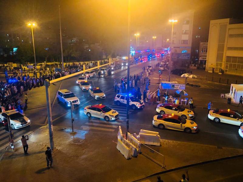 Crowds line the streets as a parade of police cars and taxis enter Al Ras and Naif on Sunday night. Officials played the national anthem and thanked residents for their cooperation after an almost month-long lockdown. The National