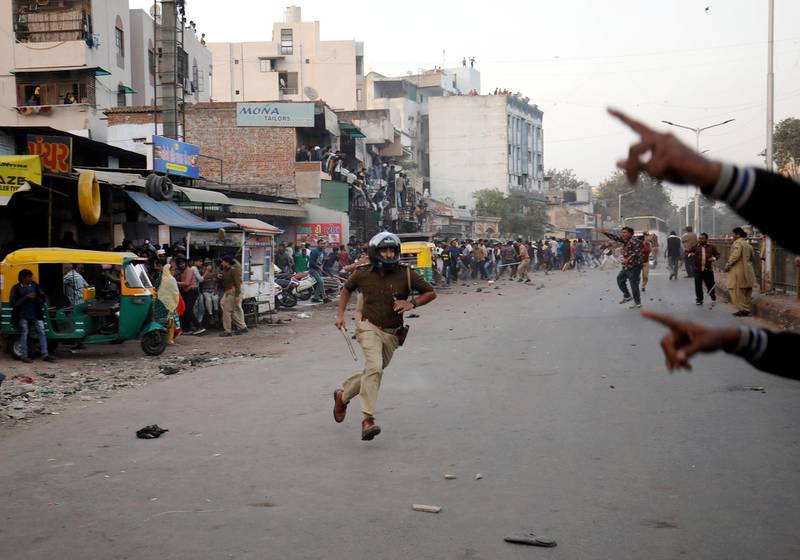 A police officer chases away demonstrators during a protest against a new citizenship law, in Ahmedabad, India.