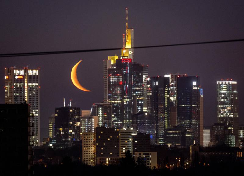 The Moon rises behind the buildings of the banking district in Frankfurt, Germany. AP