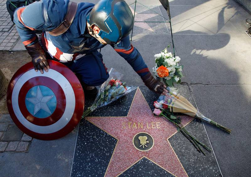 A Captain America impersonator touches the flowers covering the Walk of Fame star in memory of Stan Lee. EPA
