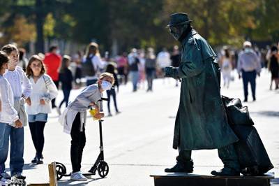 Girls wearing face masks look at a living statue at the Retiro Park in Madrid. AFP