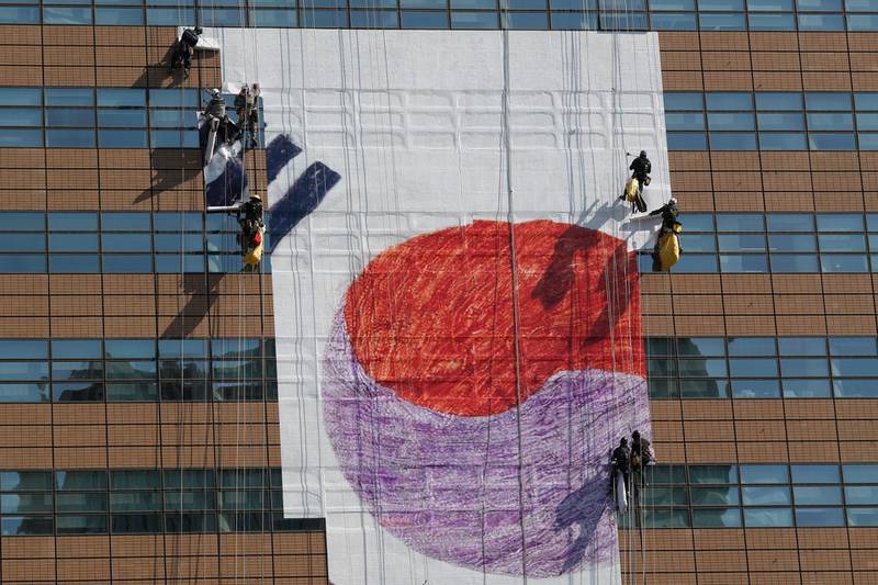 Workers install a giant national flag on the wall of a building in Seoul, South Korea. EPA