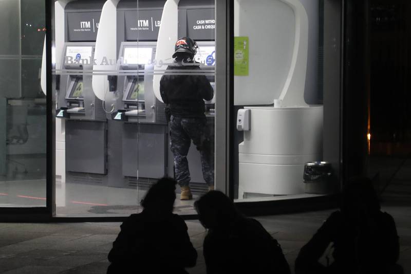 Riot police members withdraw money from an ATM at a local Bank Audi SAL bank branch during an anti-government demonstration in Beirut. Bloomberg