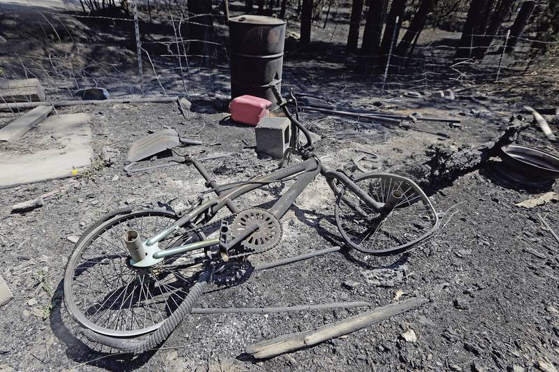 A bicycle lies among the remains of a burnt mobile home in San Ignacio, New Mexico. The New Mexican / AP