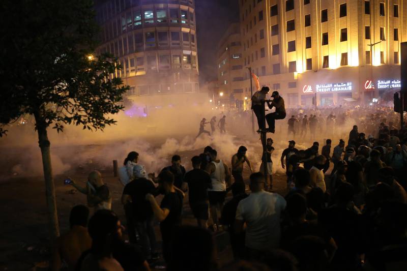 Protesters run through the smoke from tear gas after clashes with Lebanese policemen who guard the Government palace where Lebanese Prime Minister Saad Hariri gives a press statement, during a protest at downtown Beirut.  EPA
